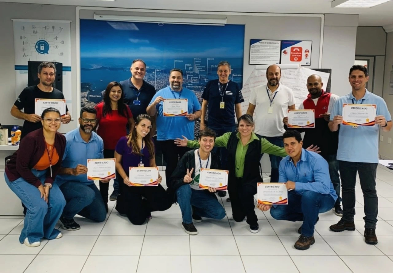 Equipe reunida em escritório segurando certificados de formação